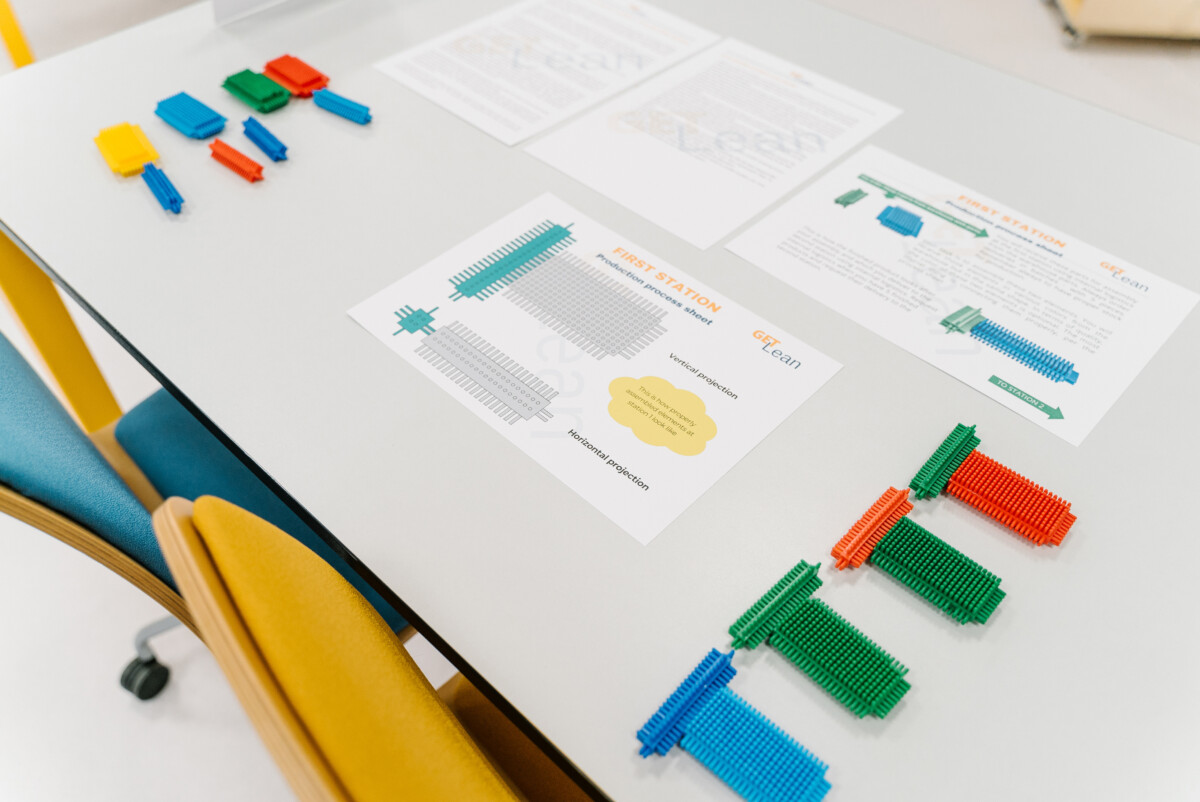 Lean games materials on a table, including colorful blocks and instruction sheets used in the GET LEAN simulation for hands-on process learning.